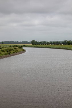 Nehir, kırsal kesimin ortasındaki yeşil çimen tarlalarına döküldü.