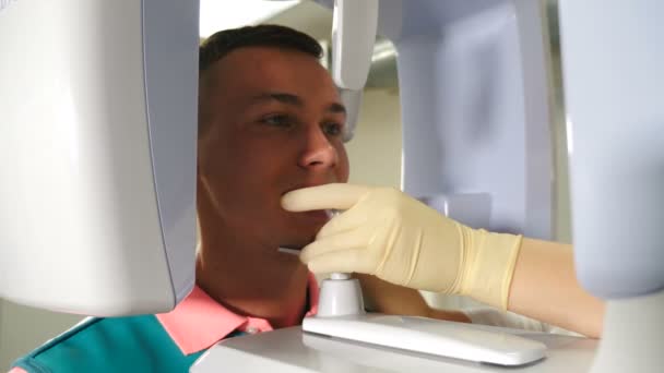歯科放射線撮影用歯科用X線機に立つ若い女性患者.歯、医学およびヘルスケアの概念。現代のCT装置。歯の顎のスキャン。パノラマX線4を受ける患者 — ストック動画