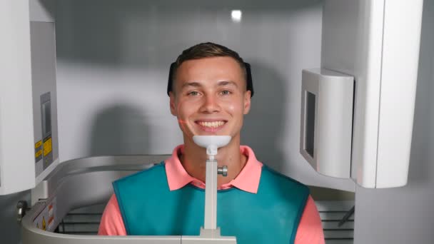 Lachend zelfverzekerde mannelijke patiënt op tandartspraktijk in MRI machine. Man die duimen laat zien na gebitscontrole. Moderne tandheelkunde. Tandheelkundige computertomografie. Röntgenfoto 's. maken van panoramische x-ray of Mri — Stockvideo