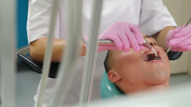 Moderne Zahnklinik mit Mikroskopwerkzeug für Behandlungspatienten. Der Zahnarzt führt einen Eingriff durch, indem er durch die Mikroskopoptik schaut. Zahnarzt mit modernen stomatologischen Geräten. 4 k video — Stockvideo