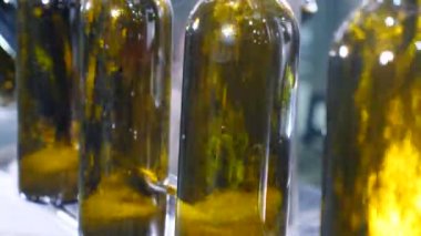 Şaraphanedeki şarap makineleriyle kahverengi cam şişeleri dolduruyorlar. Boş şişeler sıvıyla doludur. Şarap üretimi. Şarap şişeleme fabrikası. Şarabın şişelendiği işçilerle atölye çalışması. 4 k video