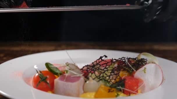 Chef at restaurant kitchen serves dish adds final ingredient and spices. Delicious tuna Fish and vegetables. Slow motion. food art gourmet dinner. adding seasonings on plate with salad. Full hd — Stock Video