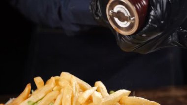 Lezzetli ev yapımı patates kızartması yapıyorum. Fast food restoranı. Patates cipsi pişirme görüntüsü. Taze Amerikan patateslerine tuz, biber ve baharat ekliyorum. Ağır çekim. Tam Hd