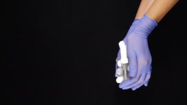 Modern dişçilik konsepti. Boş diş implantı kapları eldivenli ellerde siyah arka planda çekiliyor. Yoğun diş muayenehanesinde çok iş ve bir sürü hasta var. Dikey görüntü. Diş implantı ameliyatı. 4 bin.
