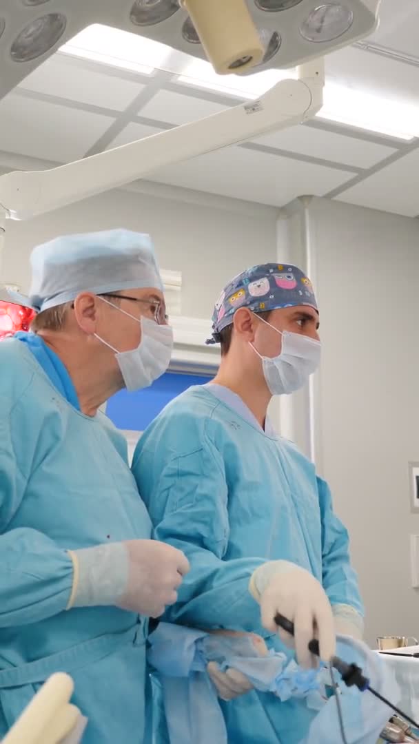 Conceito de saúde. Cirurgião com assistentes faz operação cirúrgica laparoscópica. Imagens verticais. Os médicos usam endo-instrumentos e câmeras de vídeo na cavidade abdominal. Equipamentos avançados modernos em — Vídeo de Stock