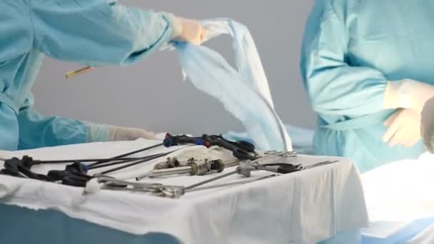 클리닉 에서의 외과 복강경 수술 준비. 수술실의 간호사가 멸균 복강경 기구를 통과하고 있습니다. 건강 과 의약품. 복강경 수술을 위한 기구를 손으로 집어 드는 외과 의사들 — 비디오