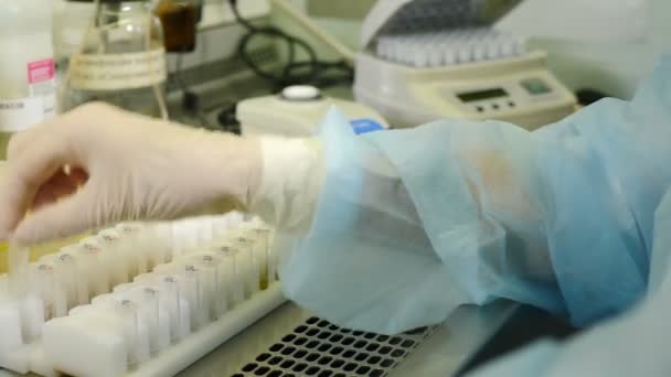 Steril genetik laboratuvarında çalışan bir bilim adamı. Sabahlıklı bir pipetle. Coronavirus analizi. Tıbbi Gelişim Laboratuvarı. Test Tüpü Sıvı ile dolduruluyor, Deney yapılıyor. DNA — Stok video