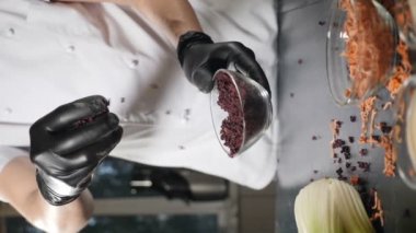 Chef in black gloves sprinkling pieces of dried sliced beet. Spices and food ingredients. Slow motion. Vertical. Mixture of colorful dried species and vegetables falling. Cleaned, washed, dried beet
