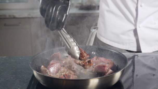 Chef cooking meat on frying pan with splashes in slow motion. Drops of water and smoke vapor come flying out of pan. Hot Pan Splashing Oil. Boiling Dish. Splashes of boiling oil. Restaurant cuisine — стоковое видео