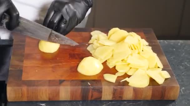 Chef In black gloves Slicing Raw Potatoes very fast. Top view. Man in Kitchen Cuts Potatoes and Prepares dish. Cooking in restaurant of natural ingredients. Healthy vegetables. 4 k video — Stockvideo