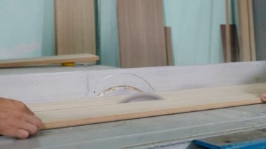 Carpenter at work cuts piece of board with circular electric saw and strokes wood with hand, Flying sawdust of working circular. Process of making wood chipboard furniture. Electric tools. 4 k video