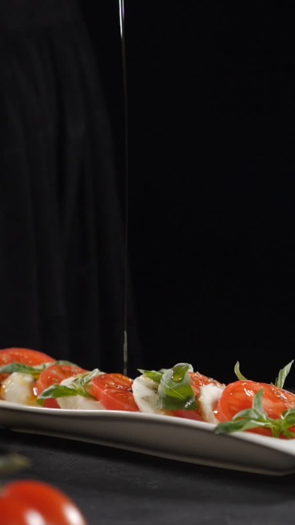 Chef verser de l'huile d'olive sur la salade de caprese. Au ralenti. Alimentation saine et végétarienne. Vue latérale. Salade de caprese italienne traditionnelle avec fromage Mozzarella et tomates. Images verticales. Full hd — Video