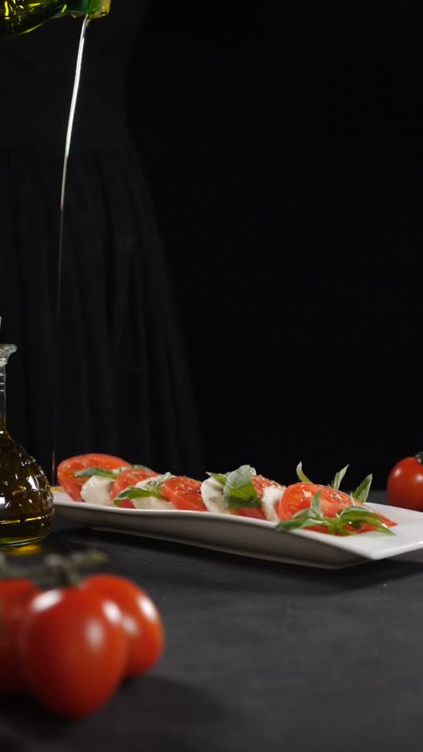 Chef vertiendo aceite de oliva sobre ensalada caprese. En cámara lenta. Comida sana y vegetariana. Vista lateral. Ensalada caprese tradicional italiana con queso Mozzarella y tomates. Imágenes verticales. Full hd — Vídeos de Stock