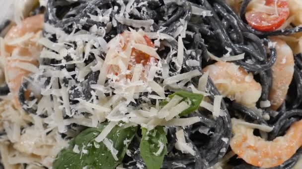 シェフは新鮮な黒魚介パスタにハードチーズをすりおろす。スローモーション。スパゲティに落ちたすりおろしたパルメザン.イタリア料理。最上階だ。レストランで料理を提供します。典型的なイタリア料理。フルHD — ストック動画