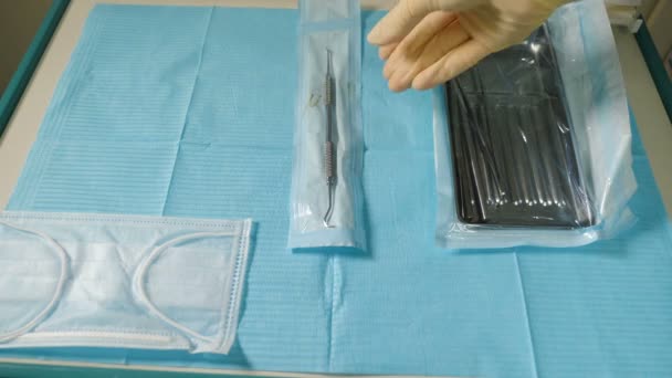 Προετοιμασία για οδοντιατρική περίθαλψη. Η νοσοκόμα βάζει οδοντιατρικά χειρουργικά εργαλεία στο τραπέζι. χειρουργικά εργαλεία πριν από την εμφύτευση στο τραπέζι βοηθός να τεθεί κάτω. Κοντινό πλάνο του βοηθού — Αρχείο Βίντεο