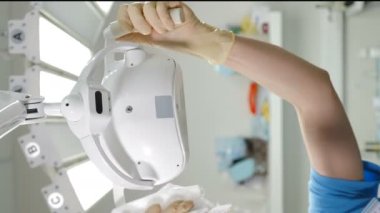 Diş kliniğinde tıbbi lamba temizleme, kabinede ameliyat tesisleri. Dikey görüntü. Klinik Hijyen Konsepti. Sterilizasyon ve dezenfeksiyon, tedavi öncesi diş bakanlığı hazırlığı