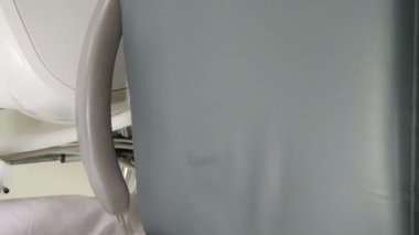 Modern diş sağlığı kliniği: tıbbi kadın temizlik ve dezenfekte koltuğu. Dikey görüntü. Ekipman ve tesis odada. Tıbbi diş ünitesinin işlenmesi, sterilizasyonu ve dezenfeksiyonu