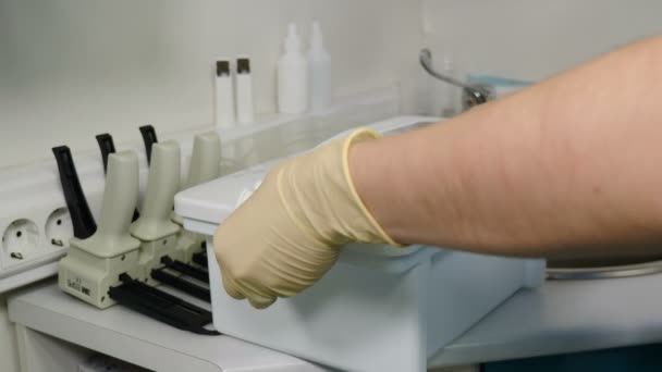 Ferramentas de esterilização, purificação bacteriana e desinfecção na clínica odontológica. Assistente de clínica dentária colocando ferramentas odontológicas usadas em solução desinfetante. Close-up. 4 k vídeo — Vídeo de Stock