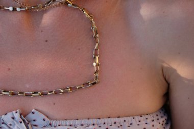 Bir kadının vücudunda eski altın, devasa bir erkek zinciri. Chad 'in el yapımı altın zinciri. Güneş ışığı.