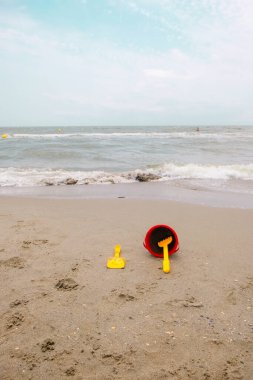 Çocuklar deniz zemininde kum için hazırlanıyorlar. Dikey resim.