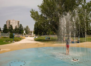 12 Temmuz 2021. Avignon, Provence, Fransa. Parktaki çeşme. Kırmızı şortlu bir kız Güney Fransa 'da sıcaktan kaçıyor..