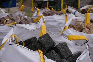 Siyah ve bej renkli kaldırım taşları sarı şeritli büyük bir torba içinde. Yumuşak kaplarda doğal taş ambalajı.