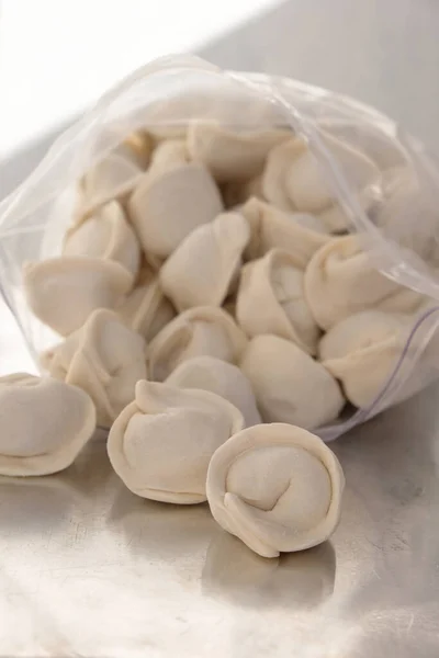 Dondurulmuş yarı pişmiş hamur köftesi ya da pelmeni. Donmuş gıda konsepti. Yemek teslimatı ve konsept yemek..