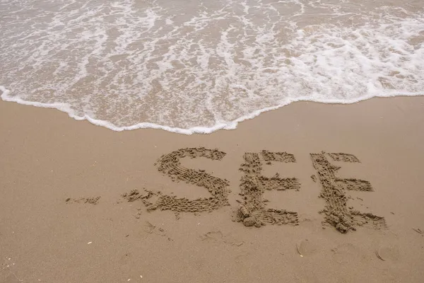 Word See Wet Sand Foamy Wave Washes Away Inscription — Stock Photo, Image