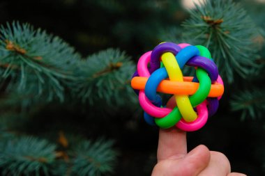 Stres önleyici top. İşaret parmağında renkli lastik düğüm topu. Spruce arkaplanı.