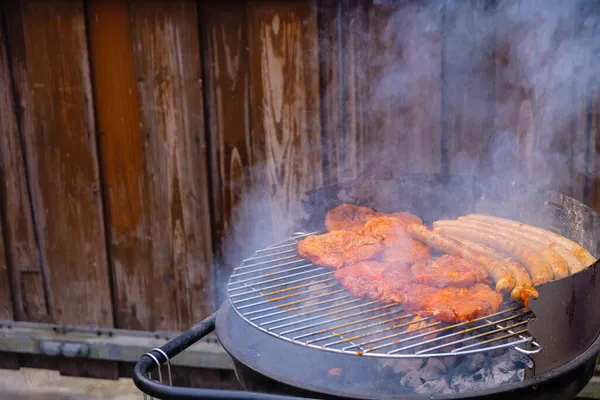 裏庭のグリルでステーキやソーセージを調理します 煙が背景をぼかす コンパクトメタルグリルセット — ストック写真