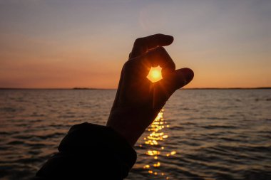 Günbatımının arka planında iyi bir jest. Göl suyundaki güneşli patika.