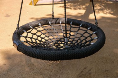 Çocuk parkında siyah yuvarlak salıncak yuvası. Yakın çekim için boş siyah ip ağ yuvası.