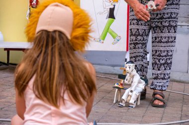 Kuklayla Sokak Performansı. Palyaço maskesini çıkarıyor. Elinde kukla olan bir kuklacı sokaktaki insanlar için gösteri yapıyor..