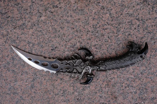 Granit arka planda kavisli bir avcı bıçağı. Boşluğu kopyala.
