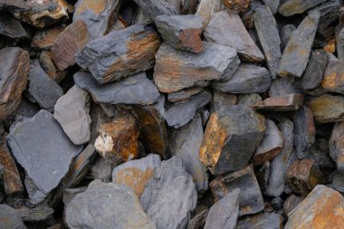 Slate stone for design. Dark gray stones with rusty spots.