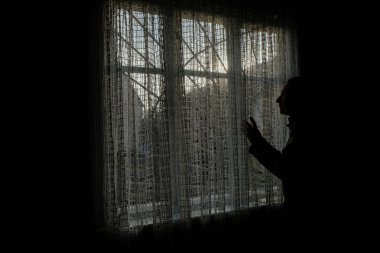 Pencere arkasında kadın silueti profili var. Pencereden dışarı bakan kadın. 