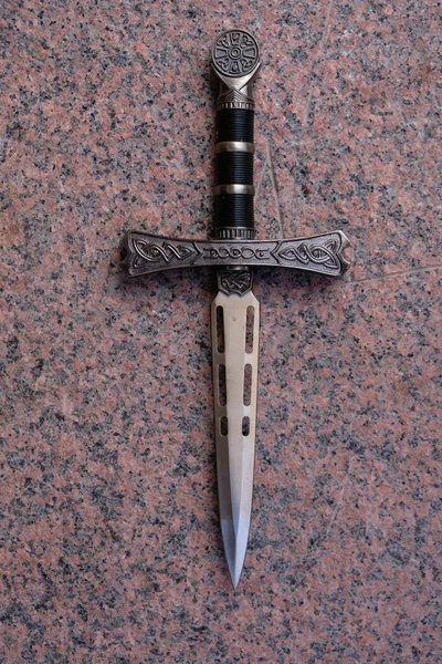Granit arka planda dekoratif bir hançer. Dikey resim.