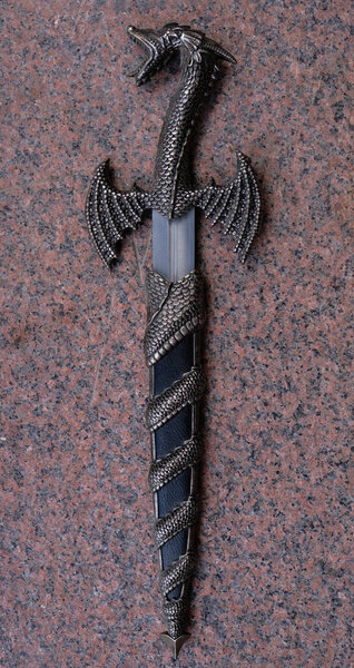 Dagger knife with a decorative handle in the form of a dragon. Vertical image.