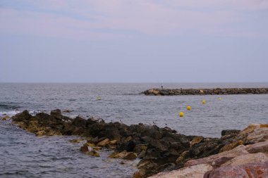 Saintes-Maries-la-mer, Camargue, Fransa yakınlarındaki dalgalar. Dalgakıranda bir balıkçının silueti..