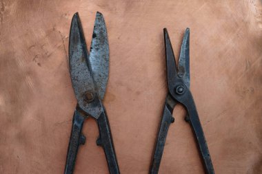 Bakır arka planda metali kesmek için iki çift eski makas..
