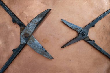 Birbirinize karşı makas açın. Bakır arka planda metali kesmek için iki çift eski makas. Saldırganlık konsepti.
