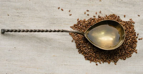 Keten tohumu yağıyla doldurulmuş kaşık. Keten bir arkaplanda keten tohumları.