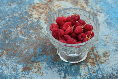 Ripe raspberries on a blue rusty background. Copy space.