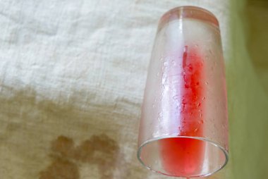 An overturned glass with the remains of cold cherry compote on a hemp tablecloth. Domestic life.