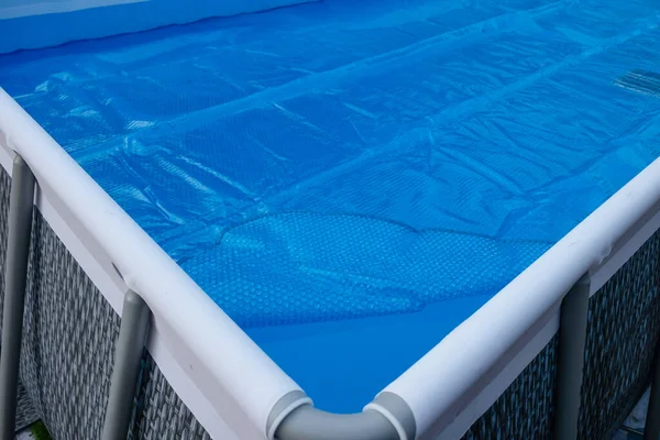 Pool cover. Blue solar film on the pool. Selective focus.