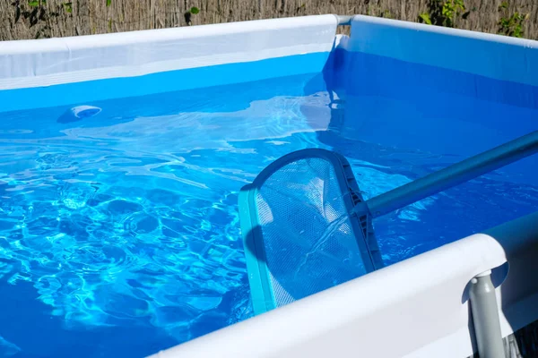 Net of the pool. Cleaning of the home pool. Blue water background. Luxury in the heat.