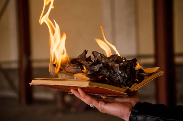 Livro de papel queima em cinzas, em telhas de concreto, queimaduras manuscritas, livro aberto com fogo na mão do homem — Fotografia de Stock