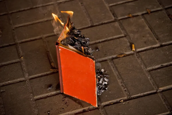 Livro de papel queima em cinzas, em telhas de concreto, queimaduras manuscritas, livro aberto com fogo — Fotografia de Stock