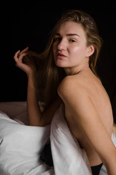 Porträtt av vacker smal ung kvinna med blont hår i en vit säng i vackra estetiska poser — Stockfoto