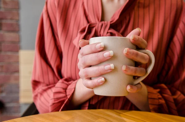 若い女性の手は カフェで木製のテーブルでラテアートとコーヒーのカップを保持し 赤いドレスの女性 — ストック写真